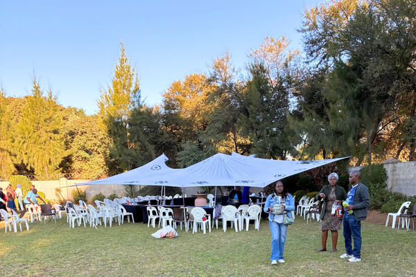 people standing in front of an outdoor tent with chairs underneath it